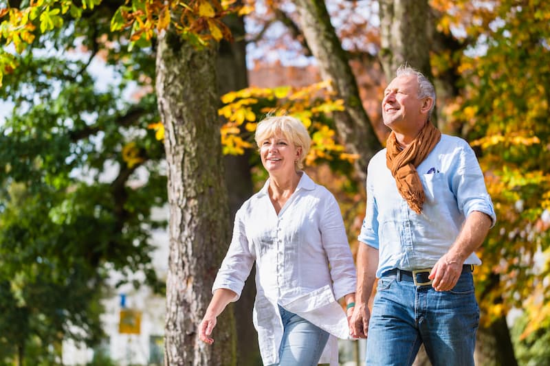 The Oaks of Garden Ridge | Senior couple walking outside through some trees